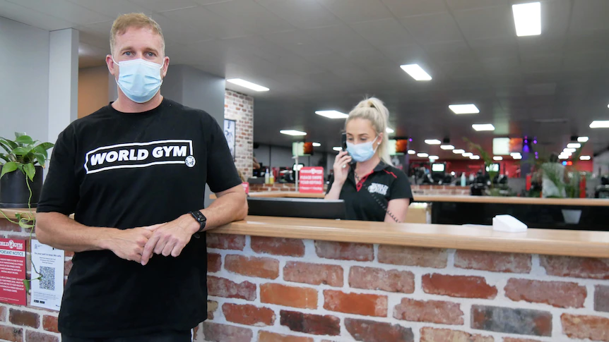 A masked man stands at a counter.