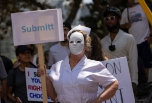 A protester dressed as a scary nurse holds a mispelled sign that reads "Submitt" at an anti-vaccination protest rally near City Hall, following the Los Angeles City Council's vote earlier this week on drafting an ordinance requiring proof of vaccination to enter many indoor public spaces in Los Angeles, on August 14, 2021. (Photo by DAVID MCNEW / AFP) (Photo by DAVID MCNEW/AFP via Getty Images)