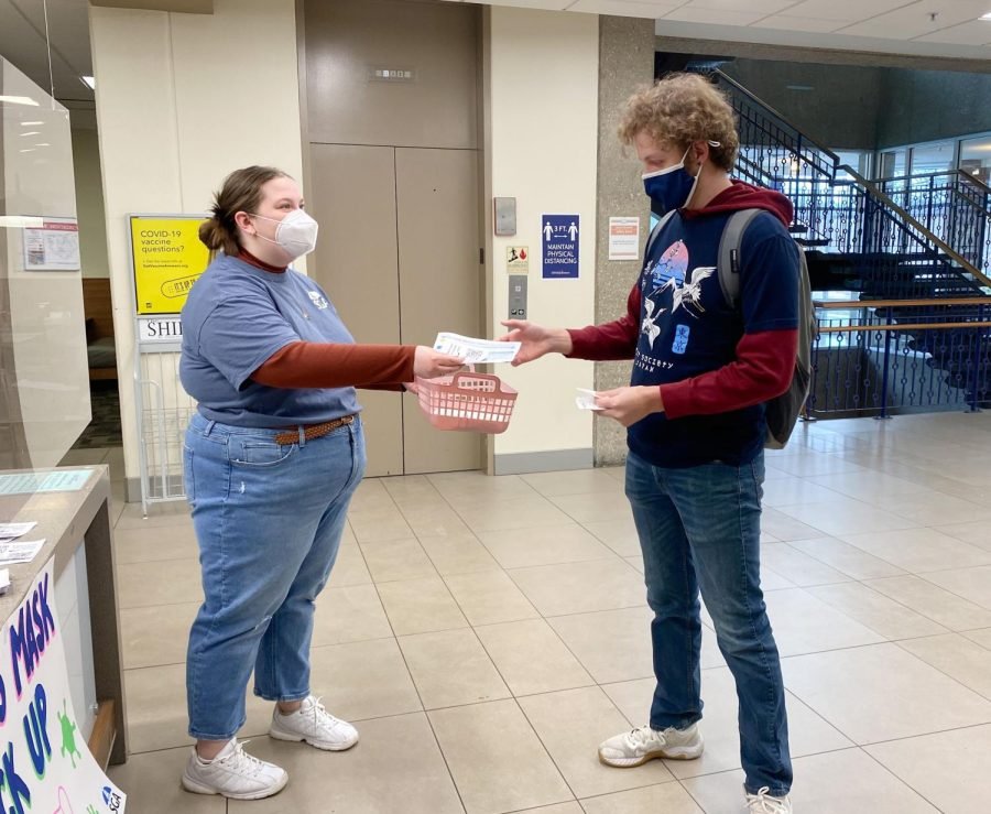 Anna+Ardelean%2C+Student+Government+Association+president%2C+hands+a+KN95+mask+and+COVID-19+information+to+Christian+Holman%2C+a+senior+sociology+major%2C+Thursday+in+the+University+Center+West.+SGA+has+been+distributing+COVID-19+masks+in+University+Center+West+Wednesday+and+Thursday.++