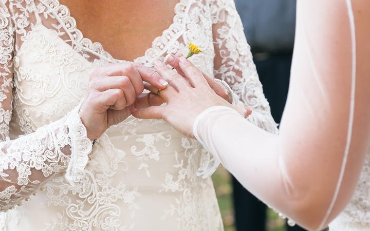 Same sex gay lesbian bride places ring on finger during wedding ceremony