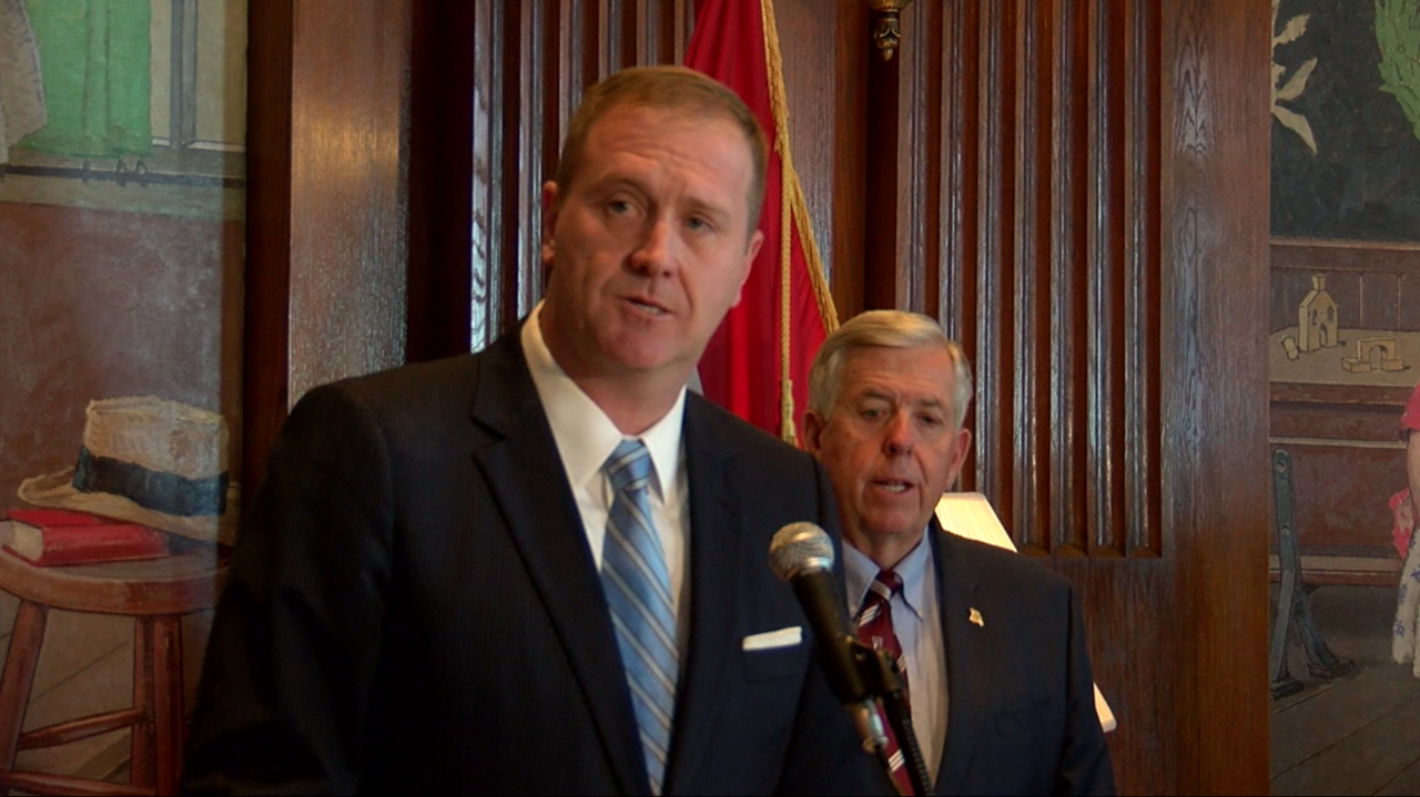 Missouri Attorney General Eric Schmitt speaks at a news conference with Gov. Mike Parson in the background.