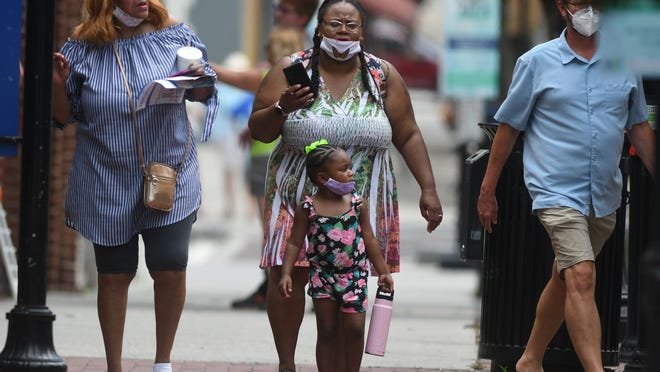 People wear masks while walking along Front St. in downtown Wilmington, N.C., Wednesday, July 15, 2020.